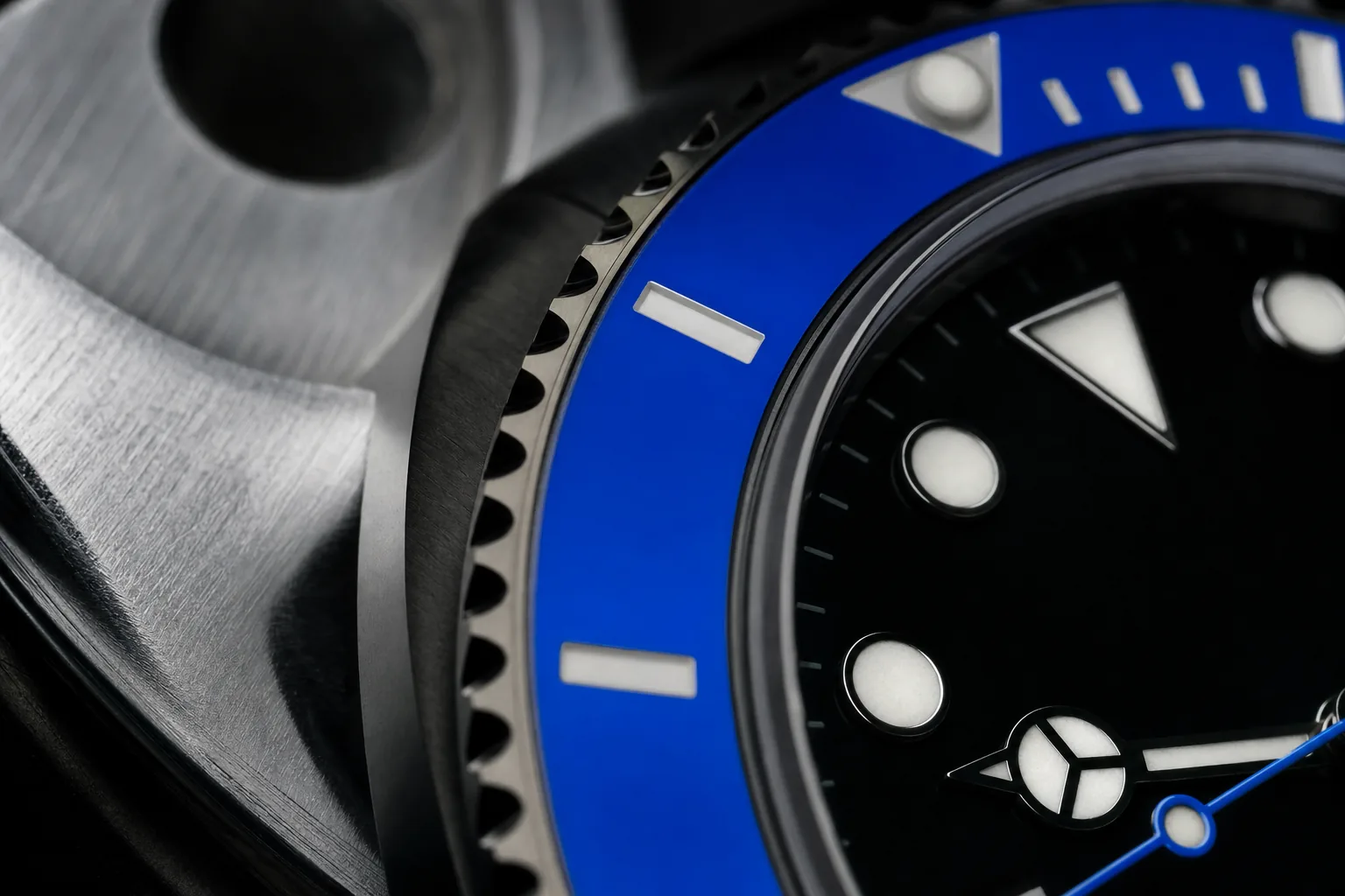 Macro detail of a black dial and blue ceramic bezel resting on brushed aluminium